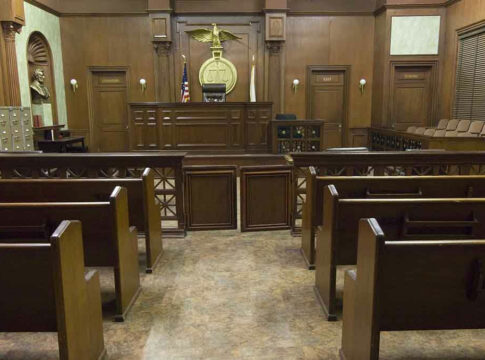 Empty courtroom with wooden benches and judges bench.