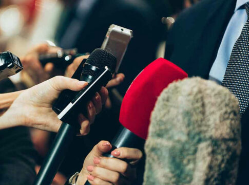 Interview microphones pointed at a person in suit.