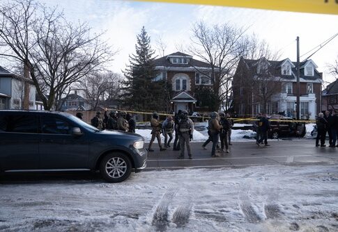 Law enforcement officers in tactical gear at a crime scene surrounded by police tape
