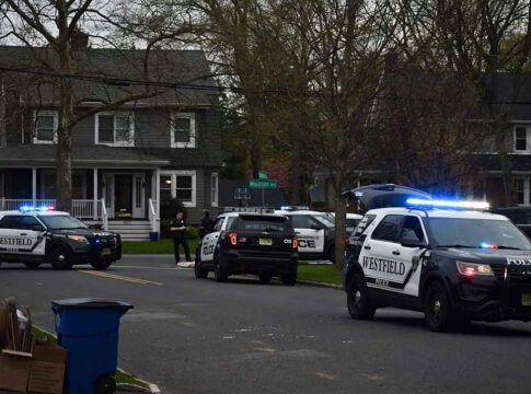 Police vehicles parked outside a house at dusk.